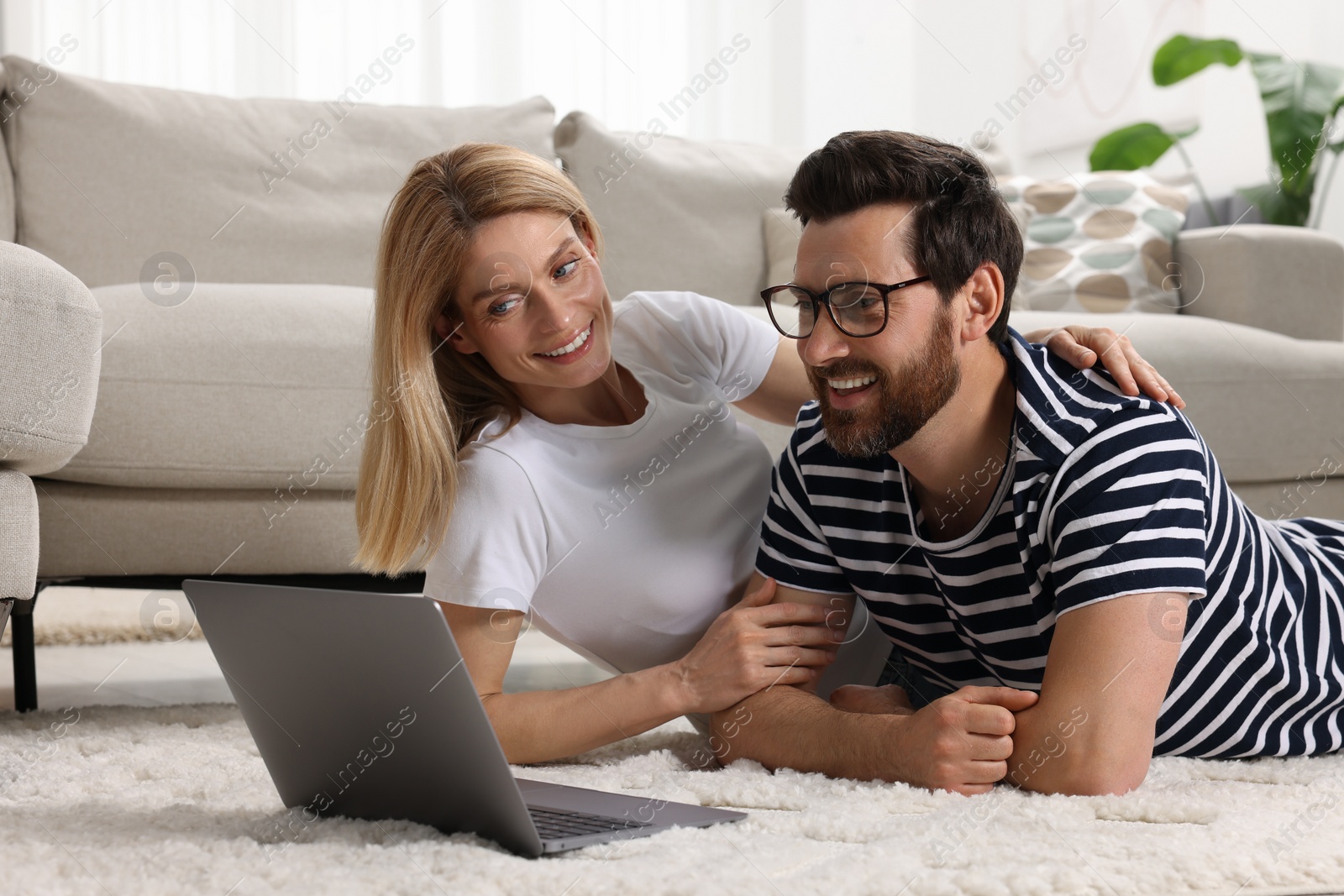 Photo of Happy couple with laptop on floor at home