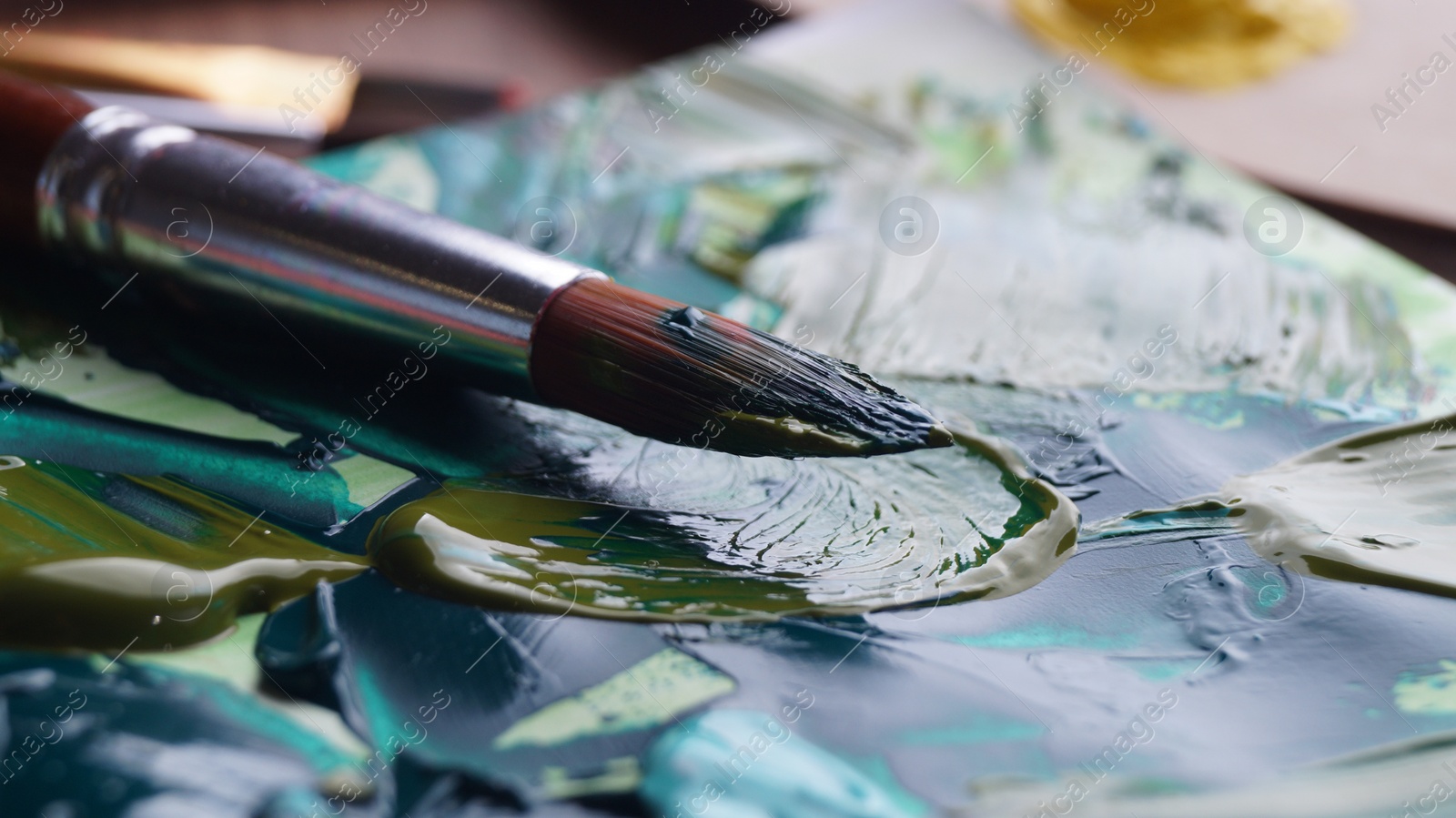 Photo of Brush on artist's canvas with mixed paints, closeup