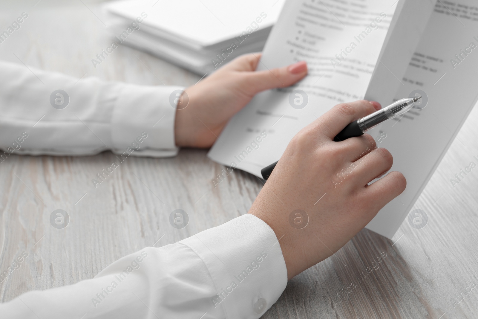 Photo of Woman reading documents at wooden table in office, closeup