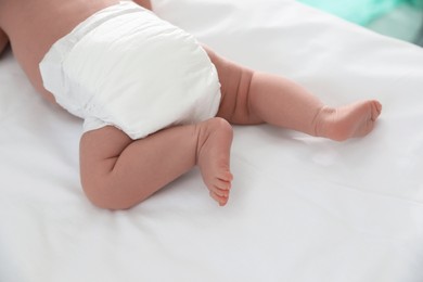 Cute little baby in diaper on bed, closeup