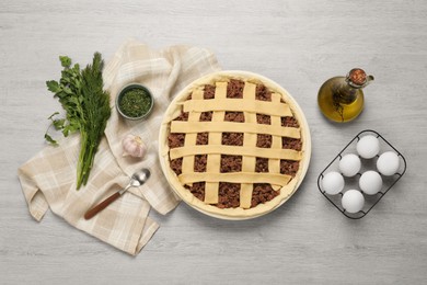 Raw meat pie and ingredients on white wooden table, flat lay