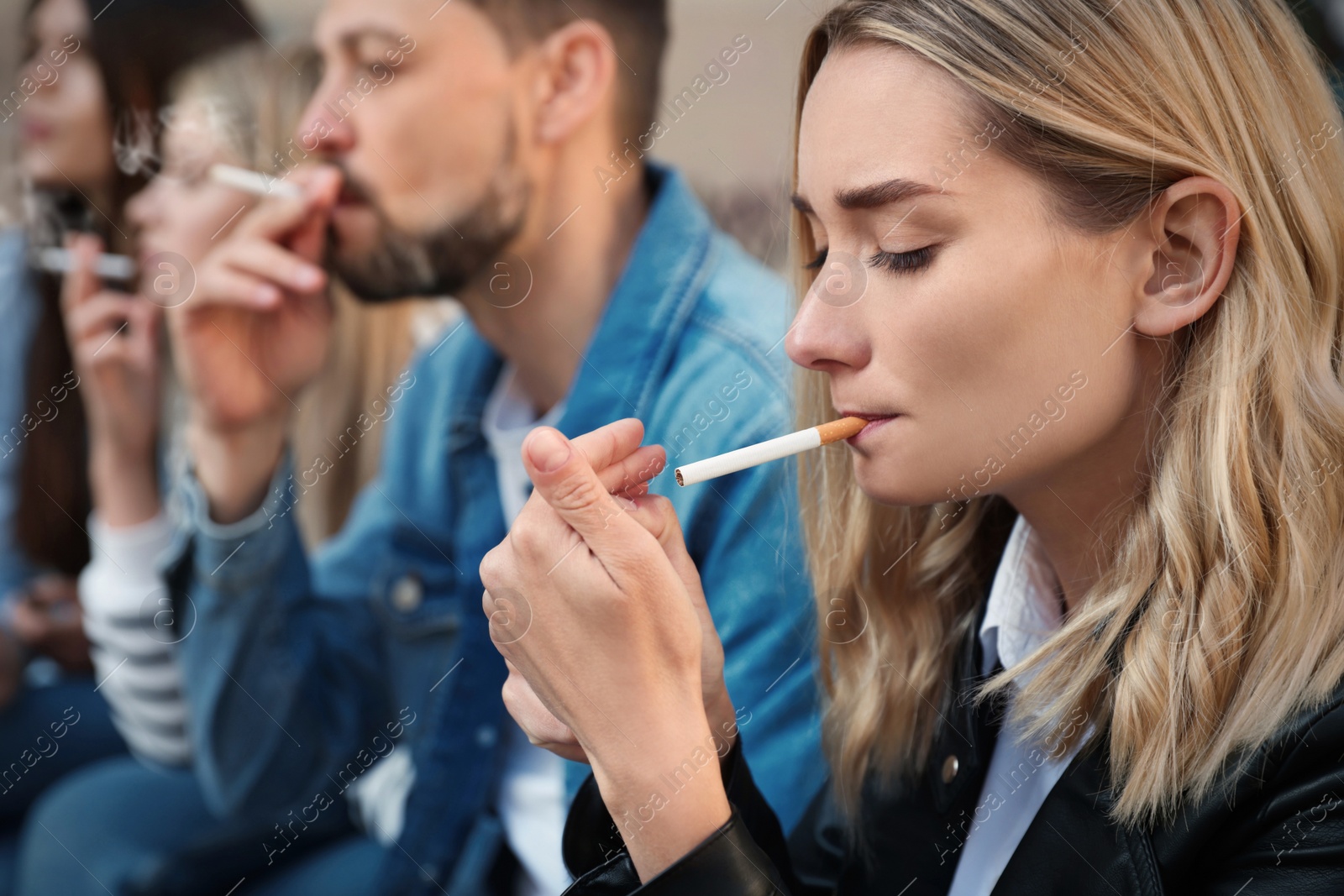 Photo of People smoking cigarettes at public place outdoors, closeup