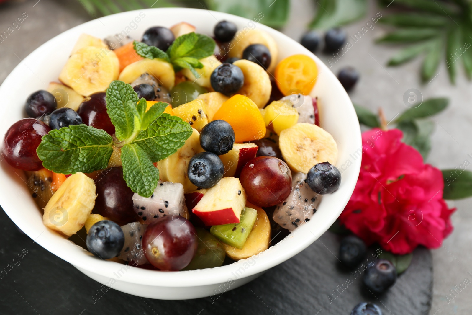 Photo of Delicious exotic fruit salad on grey table, closeup