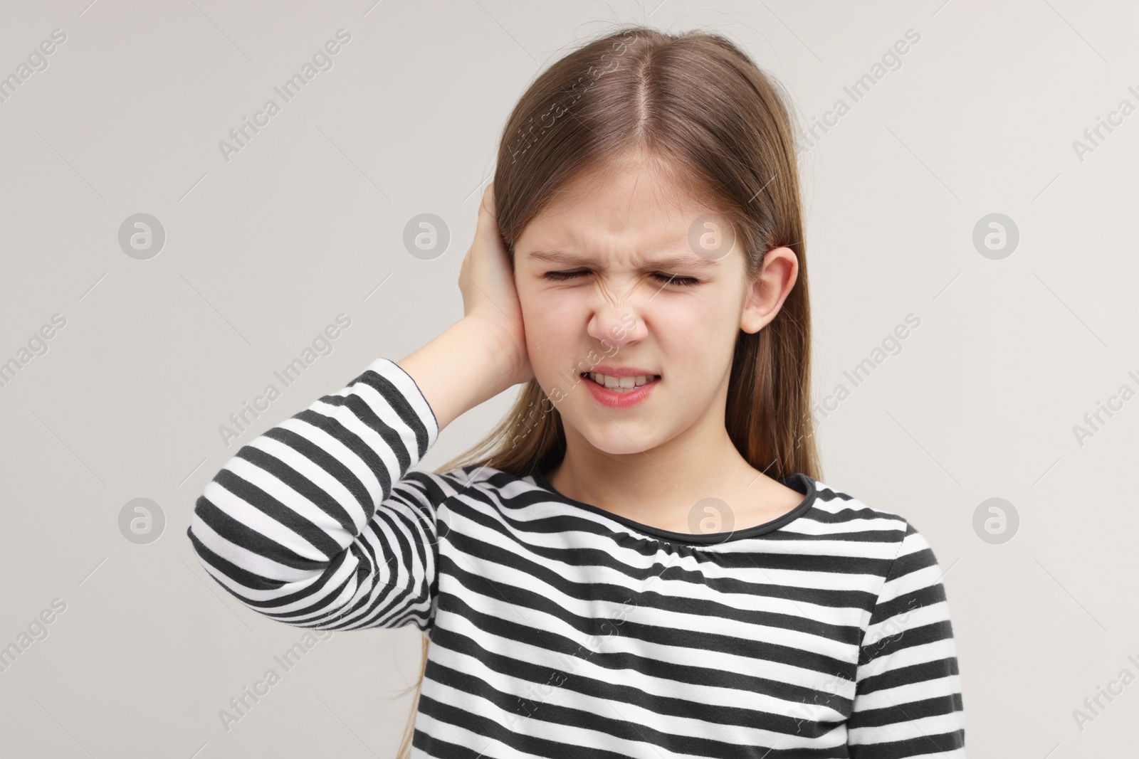 Photo of Hearing problem. Little girl suffering from ear pain on grey background