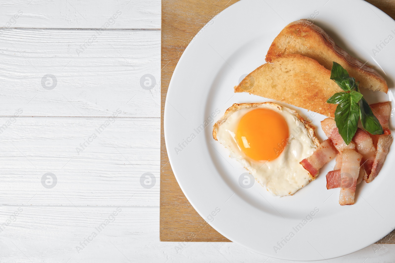 Photo of Fried eggs with bacon and toasted bread on plate served for breakfast, top view