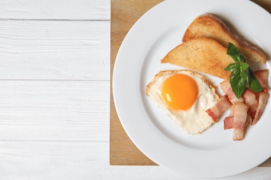 Fried eggs with bacon and toasted bread on plate served for breakfast, top view