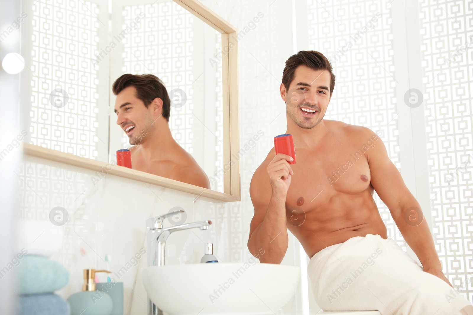 Photo of Handsome young man with deodorant in bathroom