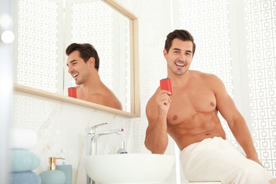 Photo of Handsome young man with deodorant in bathroom