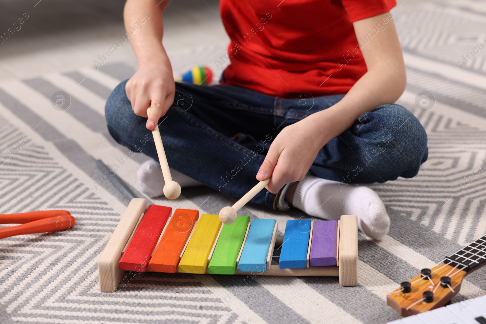 Photo of Little boy playing toy xylophone at home, closeup