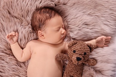 Photo of Cute newborn baby sleeping with toy bear on fluffy blanket, top view