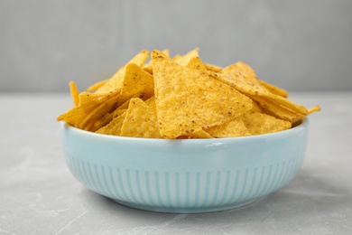 Photo of Bowl with tasty Mexican nachos chips on grey table
