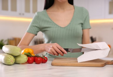 Photo of Woman wiping knife with paper towel in kitchen, closeup