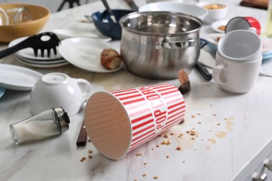 Many dirty utensils, dishware and food leftovers on white table. Mess in kitchen