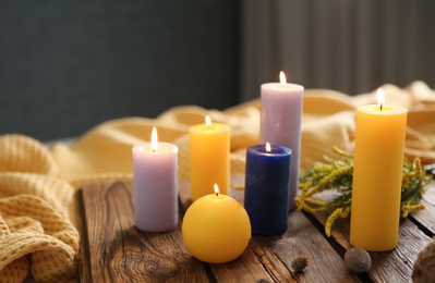 Photo of Colorful burning candles and flowers on wooden board