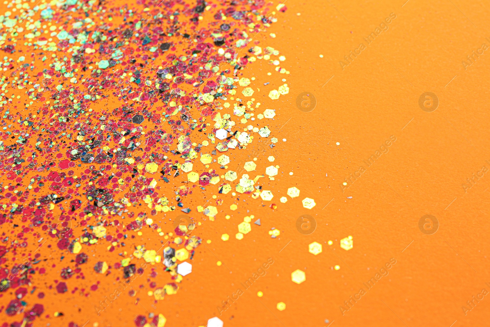 Photo of Shiny bright glitter on orange background. Space for text