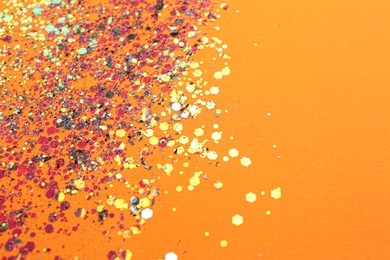 Photo of Shiny bright glitter on orange background. Space for text