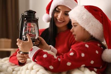 Mother and daughter playing with decorative snow globe at home