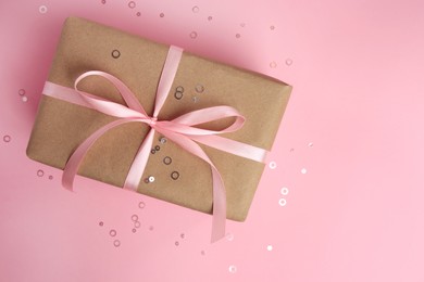 Photo of Beautiful gift box with bow and confetti on pink background, top view. Space for text