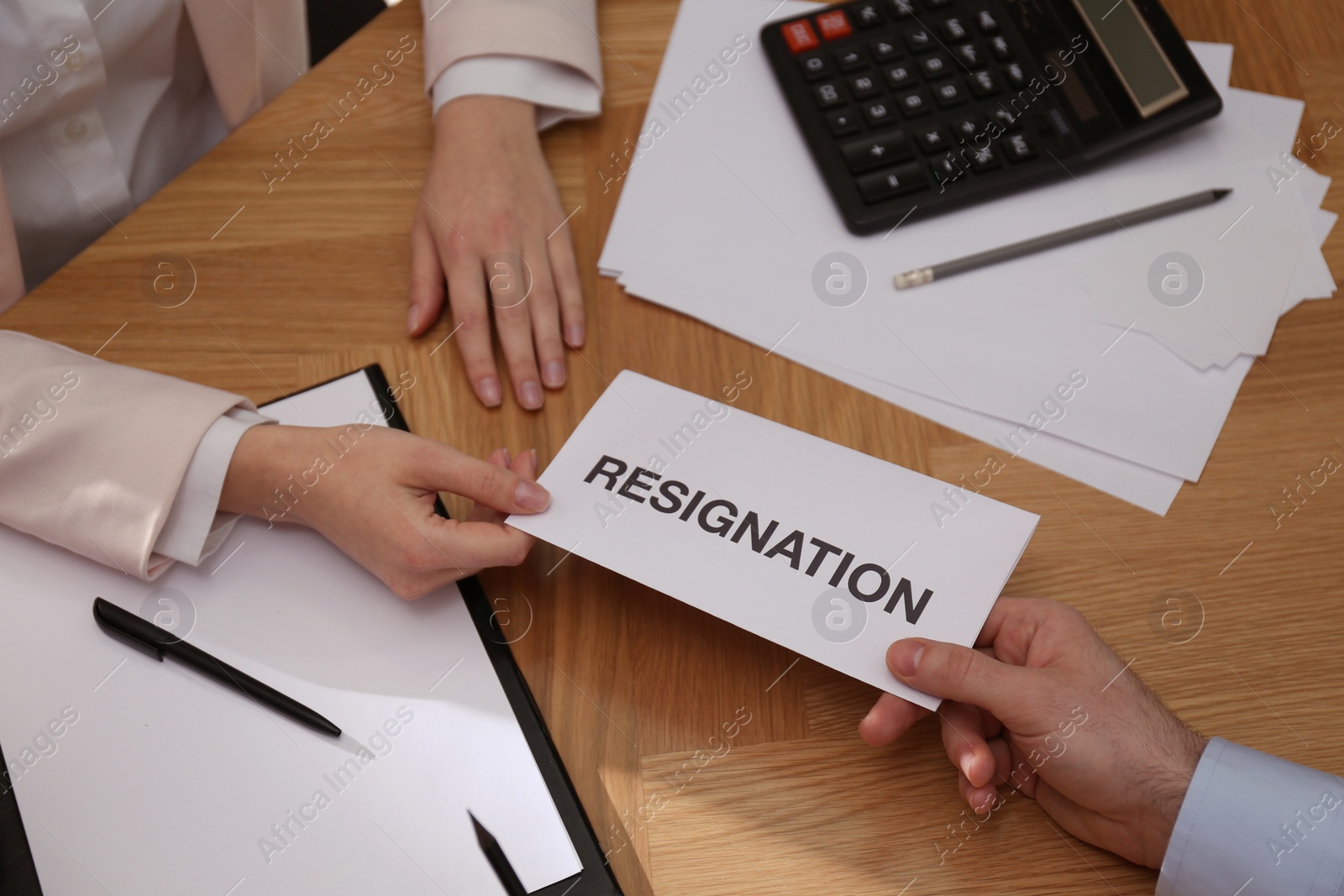 Photo of Employee giving resignation letter to boss in office, closeup