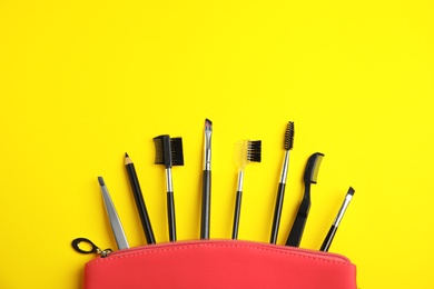 Set of professional eyebrow tools on yellow background, flat lay