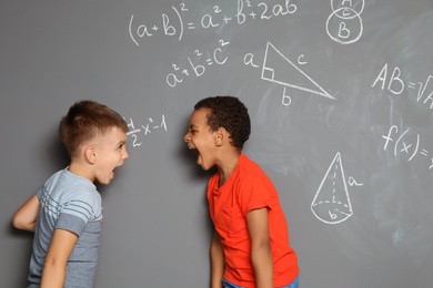 Photo of Little school children and mathematical formulas on grey background