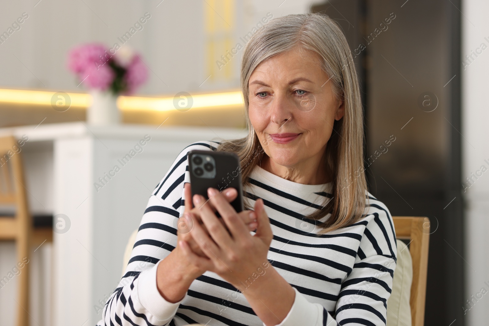 Photo of Senior woman using mobile phone at home