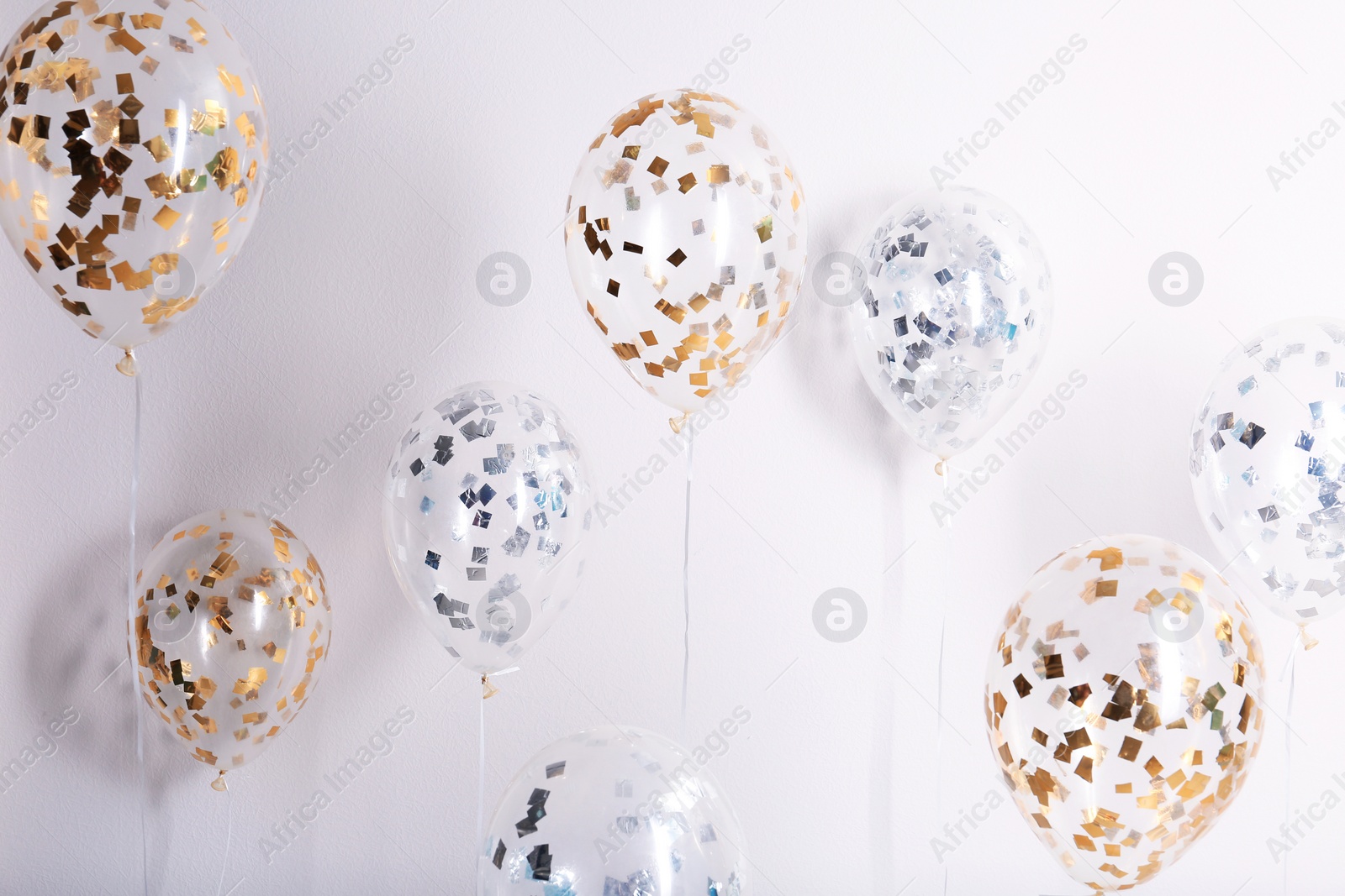 Photo of Bright balloons with sparkles on white background