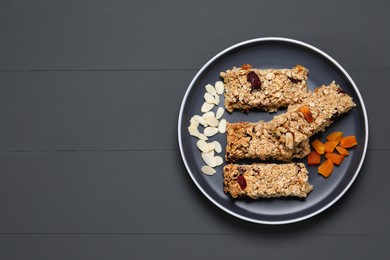 Photo of Tasty granola bars on grey wooden table, top view. Space for text