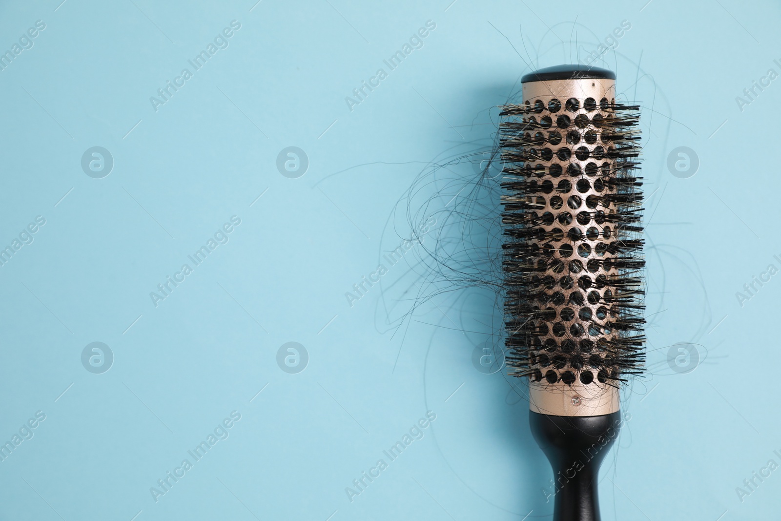 Photo of Professional brush with lost hair on light blue background, top view. Space for text