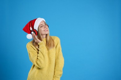 Photo of Happy woman with headphones on blue background, space for text. Christmas music