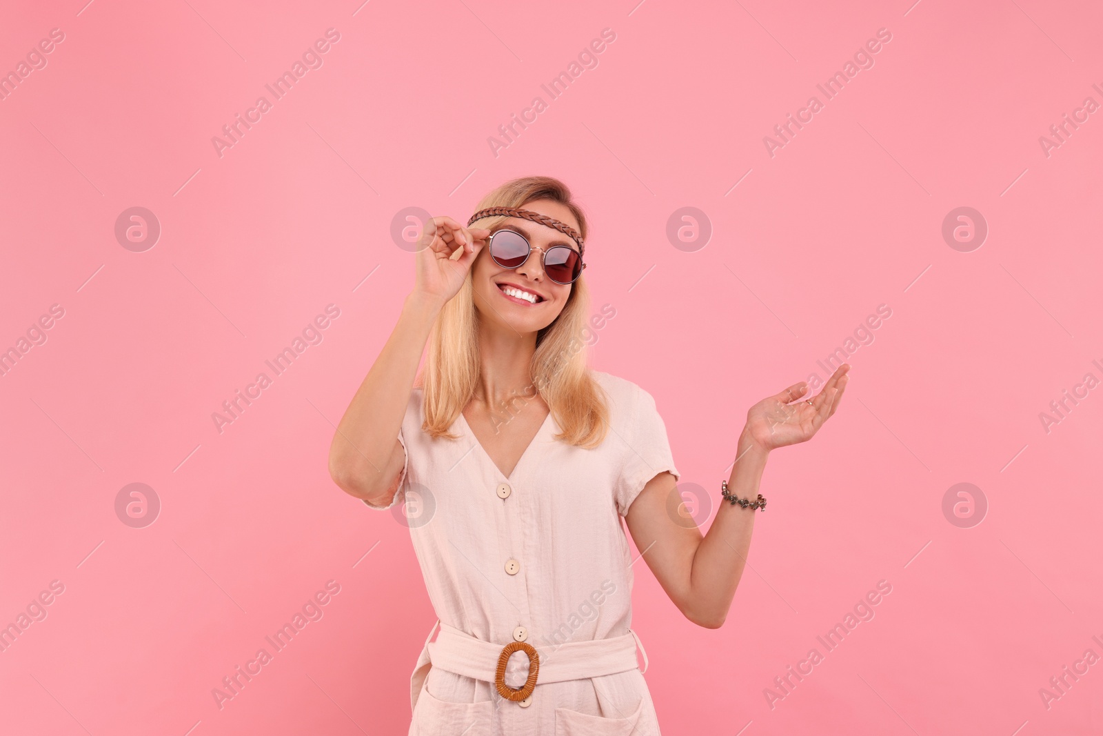 Photo of Portrait of smiling hippie woman in sunglasses on pink background