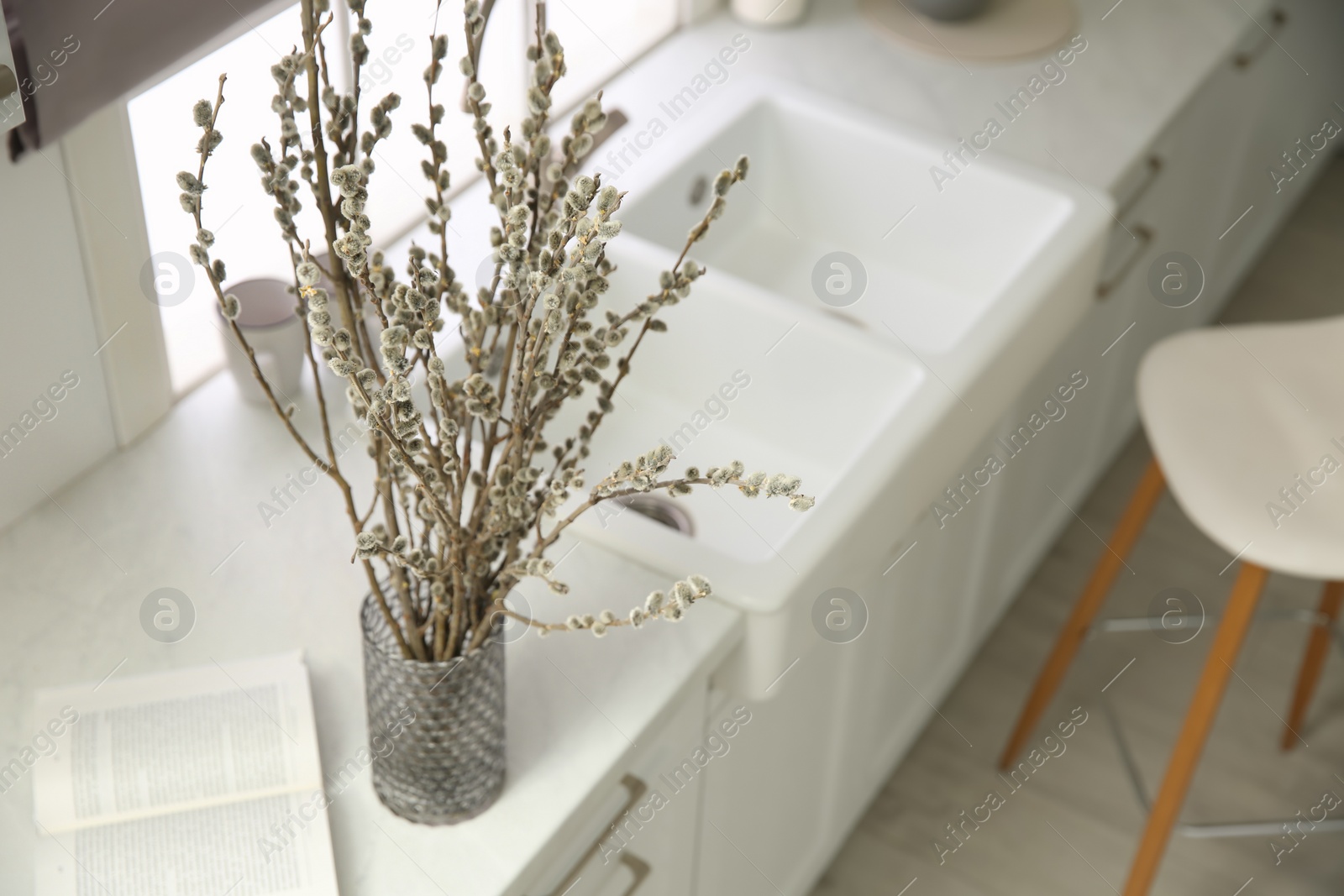 Photo of Beautiful blooming pussy willow branches in kitchen, space for text