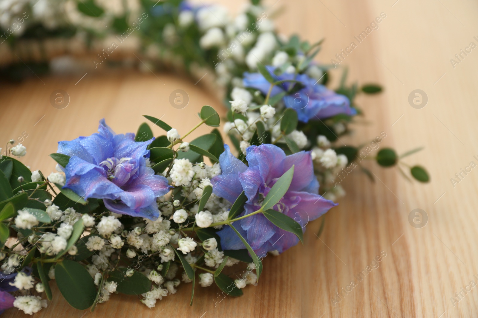 Photo of Beautiful flower wreath on wooden background, closeup