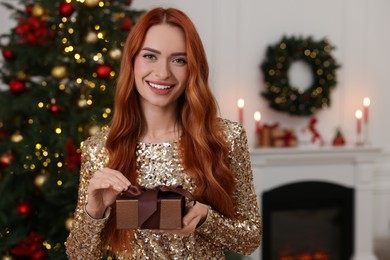 Photo of Happy young woman with Christmas gift at home, space for text