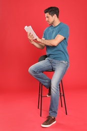 Photo of Handsome man reading book on color background