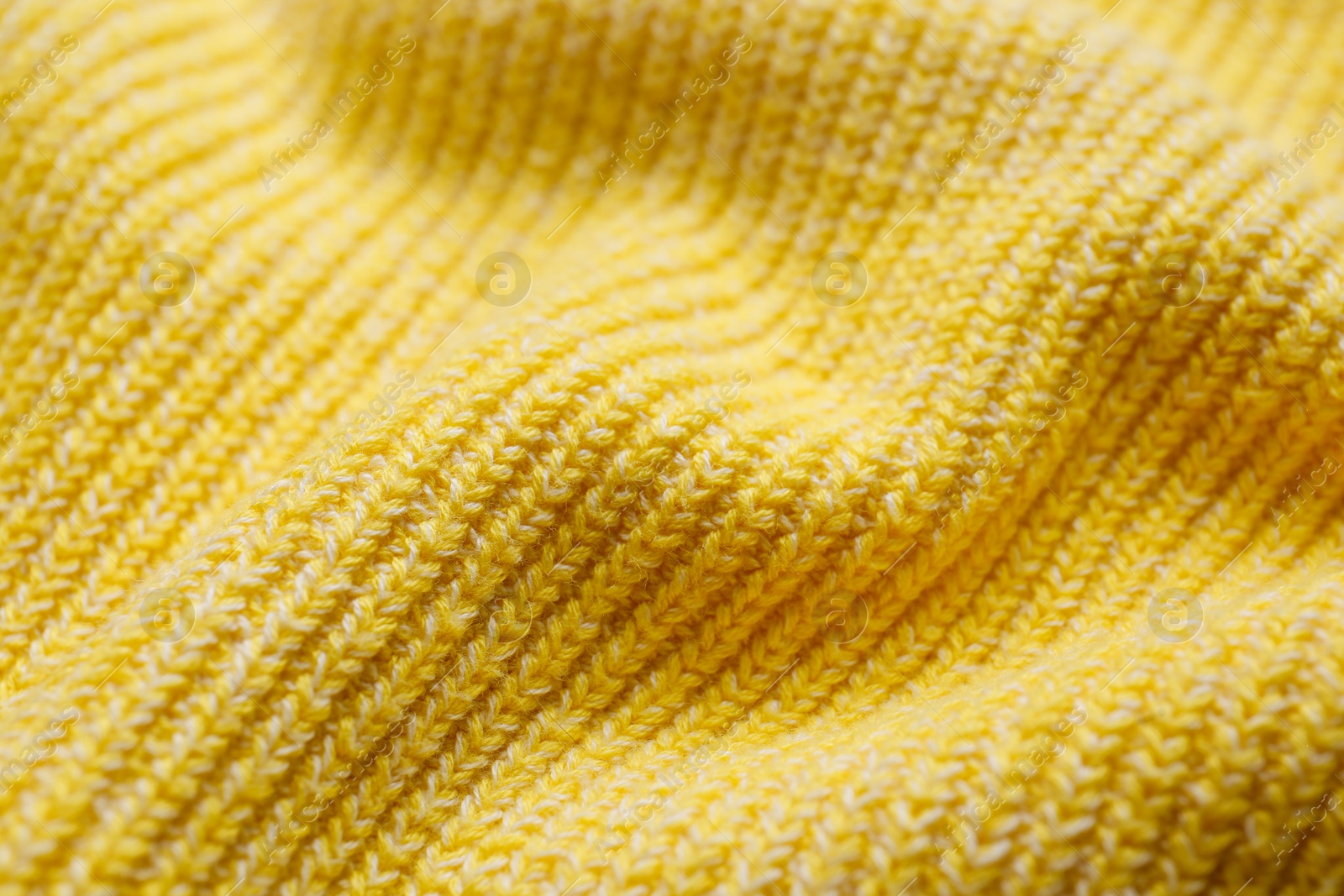 Photo of Yellow knitted fabric as background, closeup view