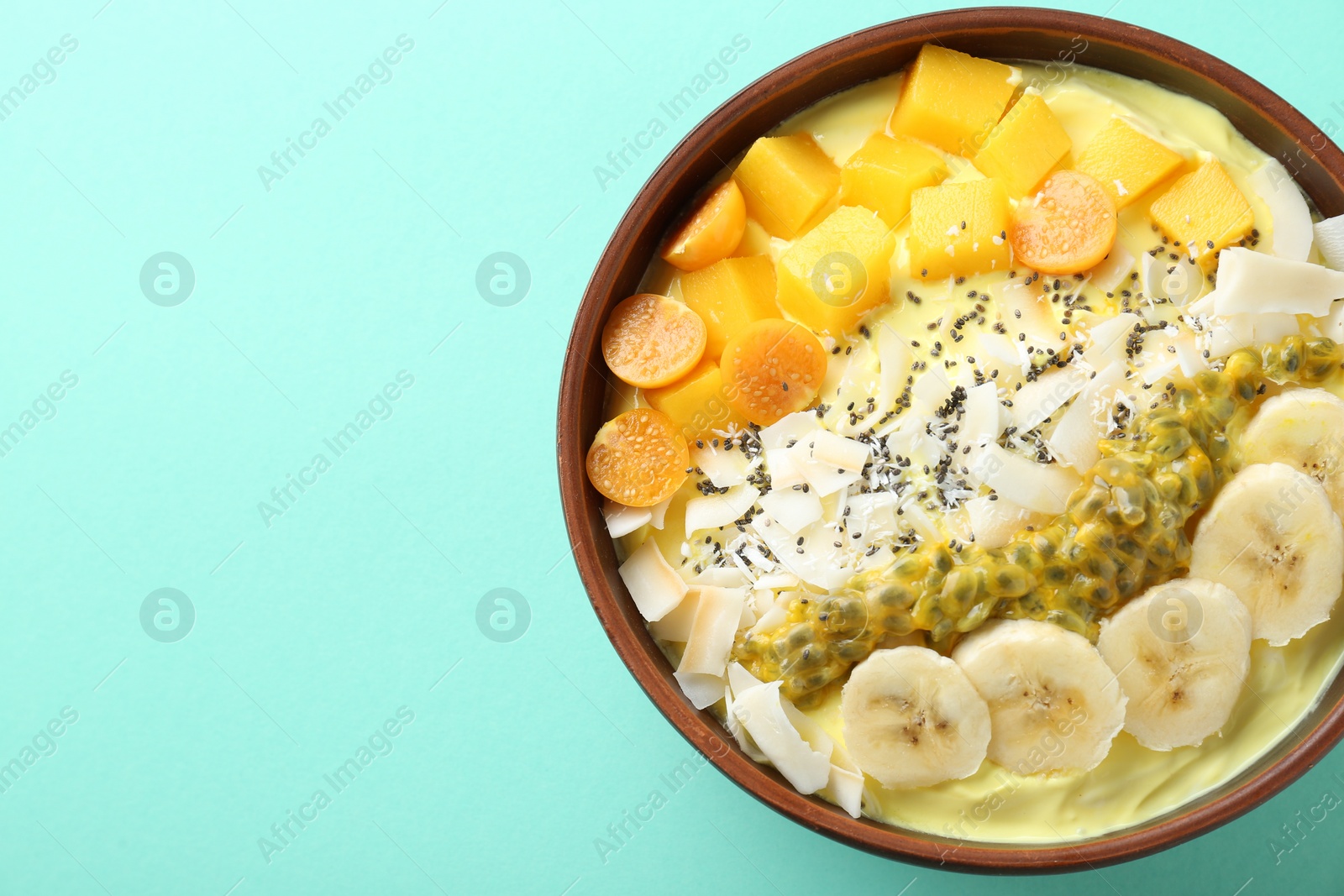 Photo of Tasty smoothie bowl with fresh fruits on turquoise background, top view. Space for text