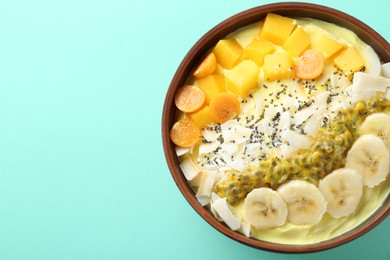 Photo of Tasty smoothie bowl with fresh fruits on turquoise background, top view. Space for text