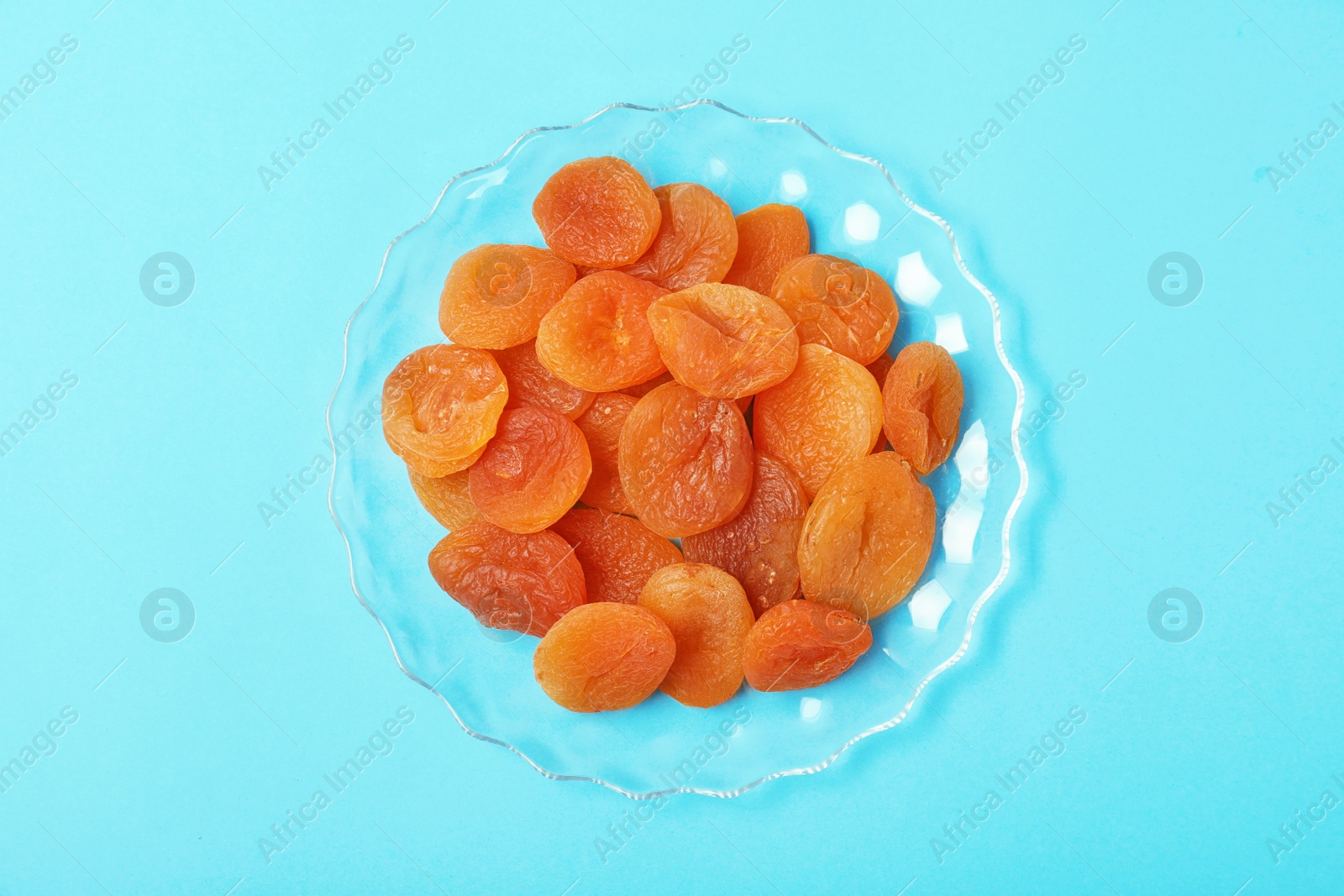 Photo of Plate with dried apricots on color background, top view. Healthy fruit