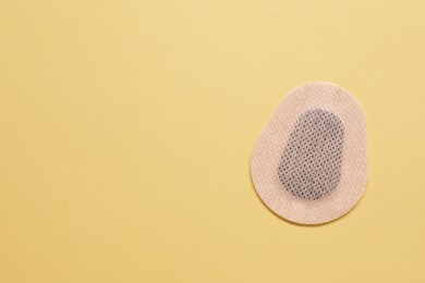 Photo of Contraceptive patch on yellow background, top view. Space for text