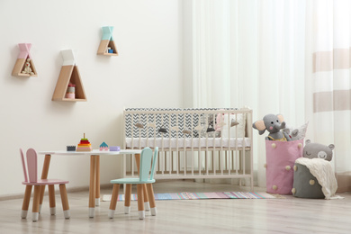 Photo of Cute baby room interior with cot and little table