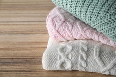 Image of Stack of folded warm sweaters on wooden table, closeup