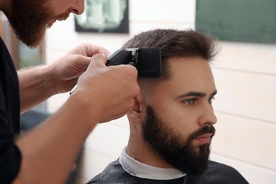 Photo of Professional hairdresser working with client in barbershop, closeup