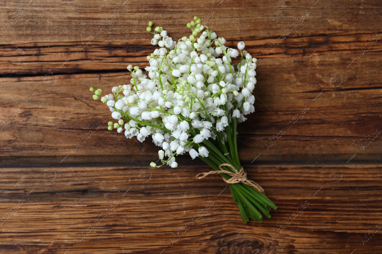 Photo of Beautiful lily of the valley flowers on wooden table, top view
