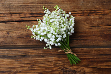 Beautiful lily of the valley flowers on wooden table, top view