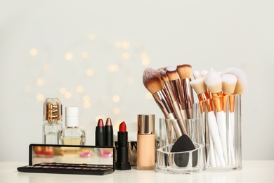 Photo of Set of cosmetic products and makeup brushes on dressing table