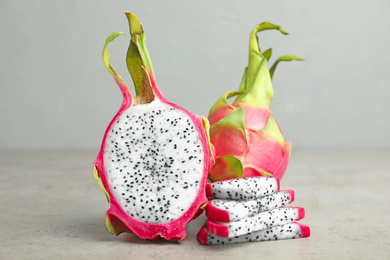 Photo of Delicious cut and whole dragon fruits (pitahaya) on grey table