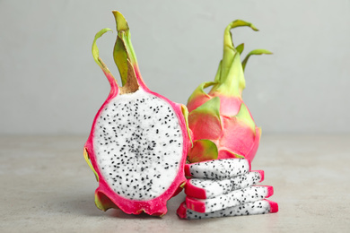 Delicious cut and whole dragon fruits (pitahaya) on grey table