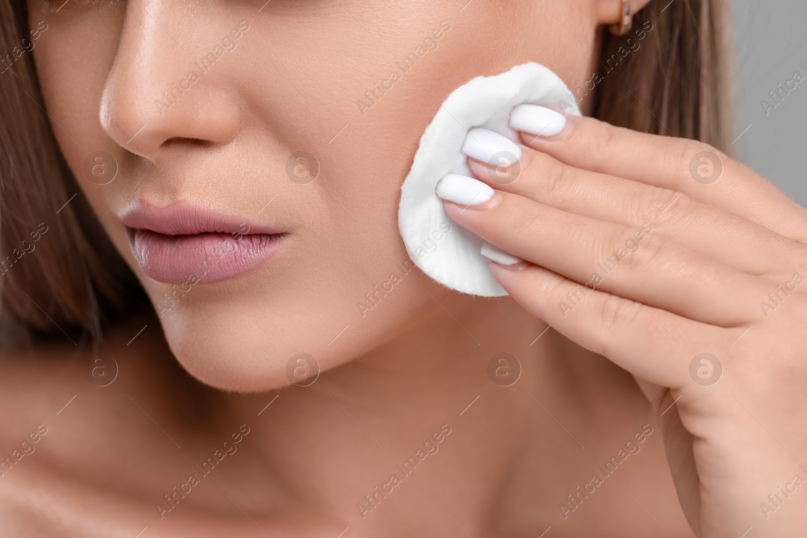 Photo of Woman removing makeup with cotton pad, closeup