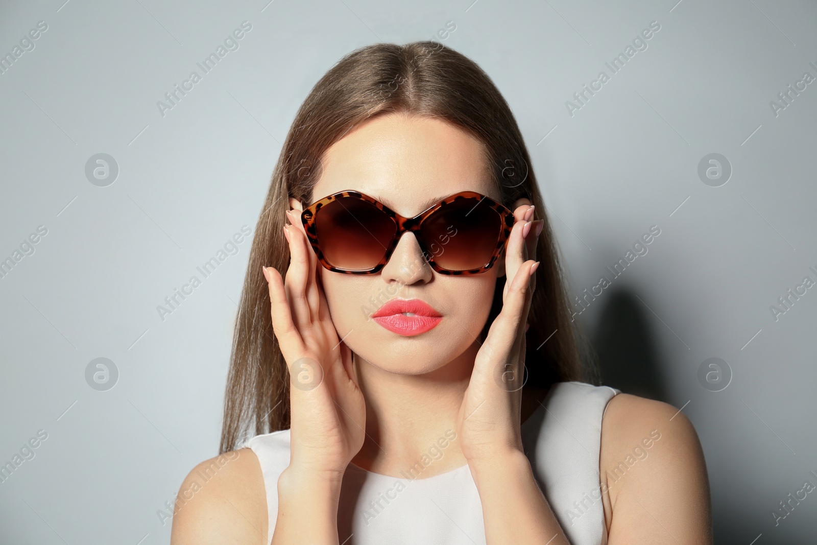 Photo of Young woman wearing stylish sunglasses on light grey background